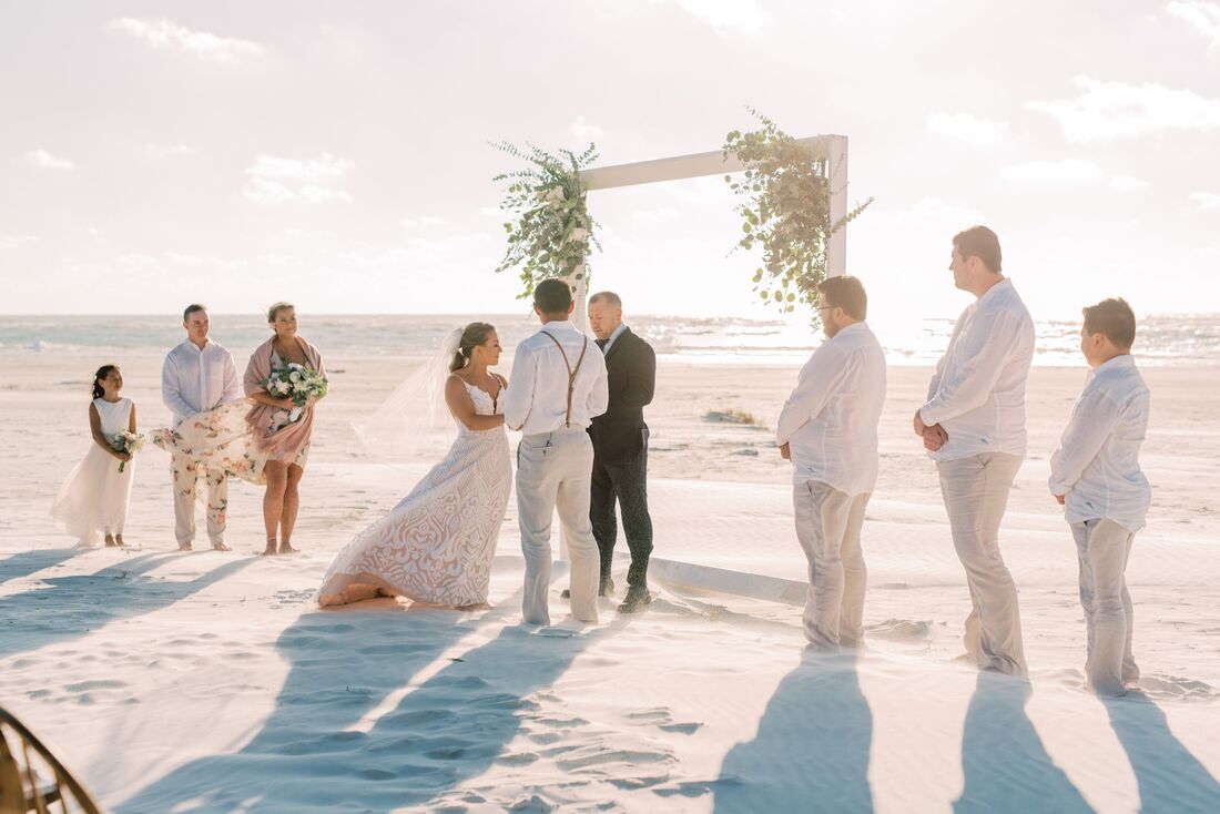 Bride and groom exchanging wedding vows on Siesta Key surrounded by family and friends