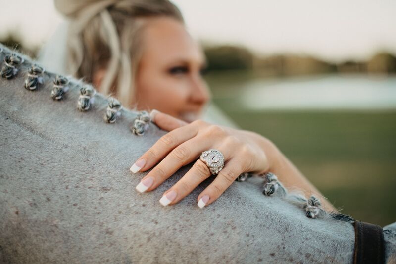 bride holding her horse showing her new wedding ring