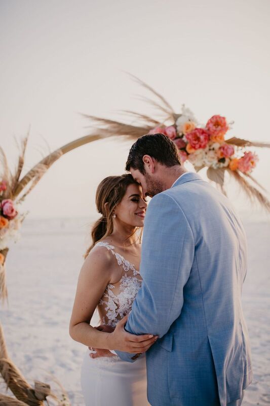 bride and groom kissing infant of their beach-Boho wedding structure