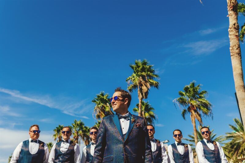 groom and groomsmen in blue suits against a blue sky