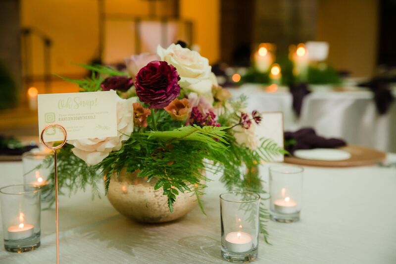 wedding recaption table with a gold metal bowl filled with pink and burgundy flowers