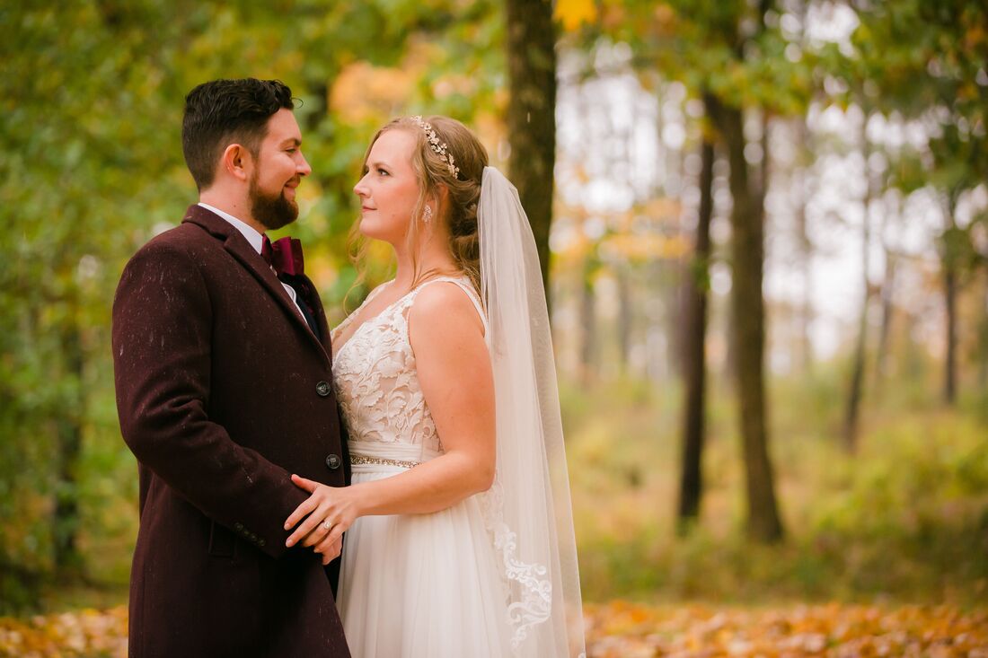 Bride and groom staying in the forrest with fall leaves around them