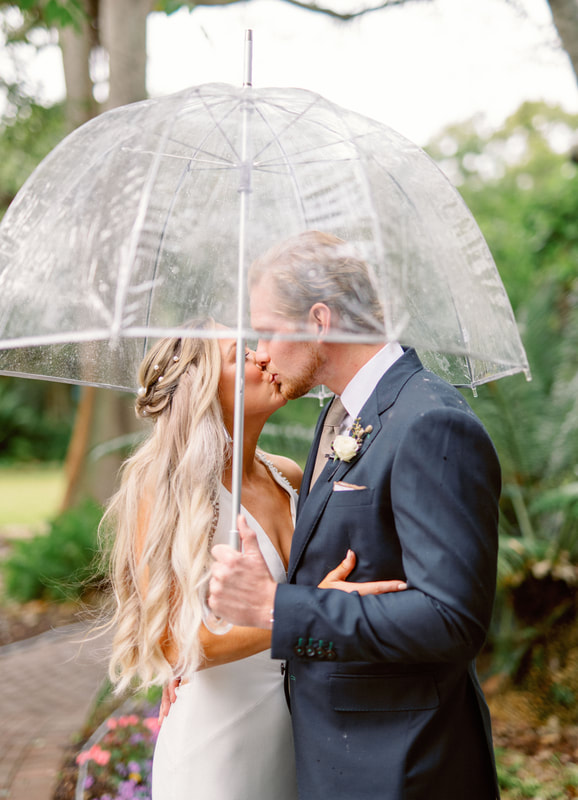 bride and groom kissing under a clear umbrella 
