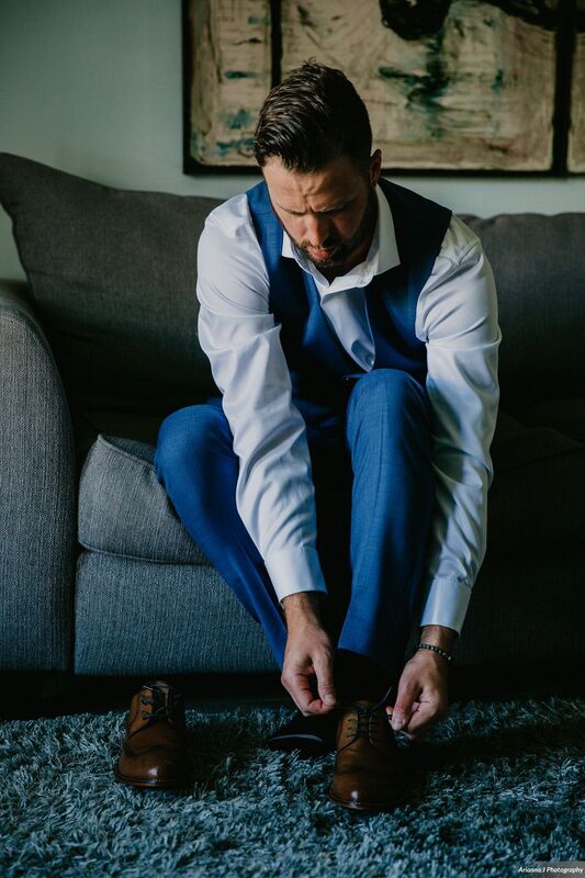 groom in blue suit putting on his shoes