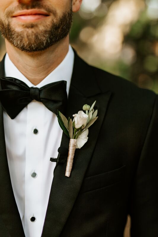 groom wearing a tuxedo with a delicate white boutonniere