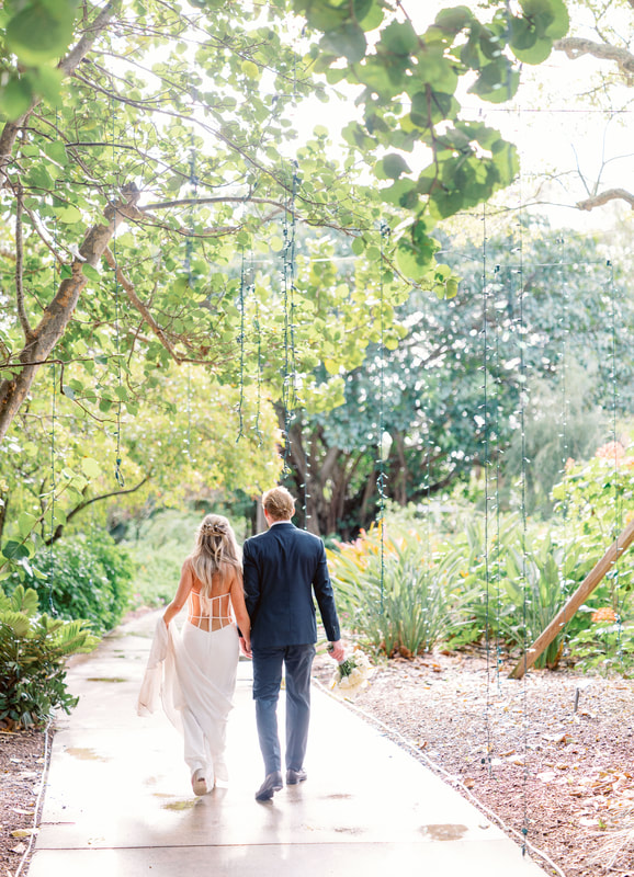 bride and groom holding hands walking through Selby Gardens on their wedding day