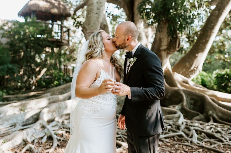 bride and groom kissing under a tree at Marie Selby Botanical Gardens in Sarasota Florida