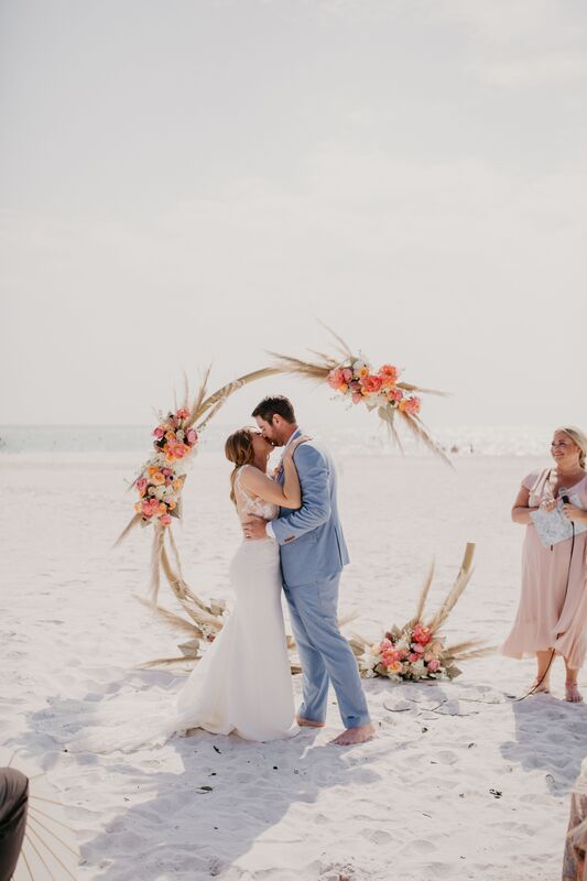 bride and groom kissing infant of their beach-Boho wedding structure