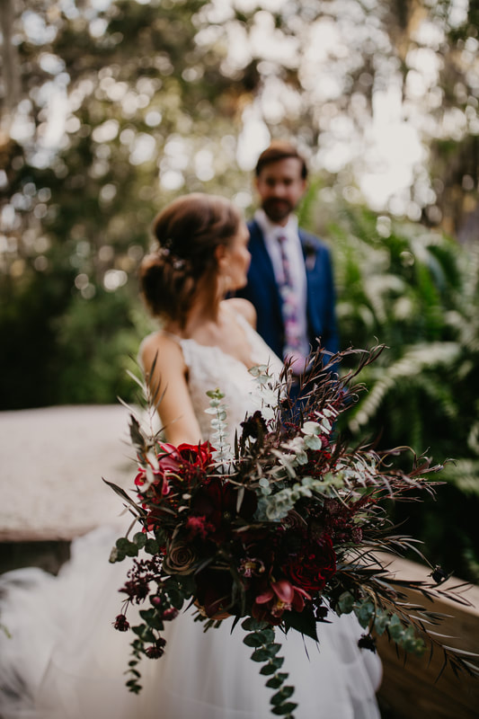 bride showing a luxurious textured bridal bouquet with burgundy flowers and textures