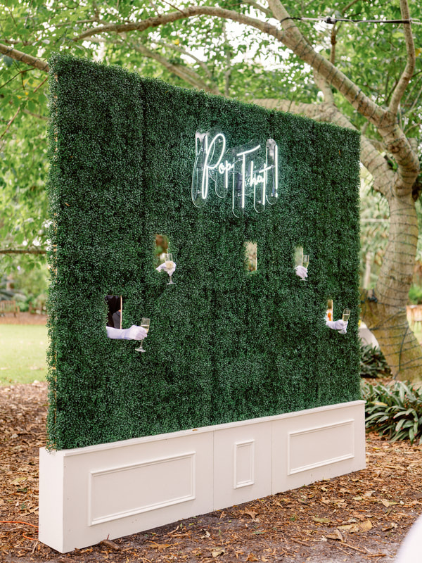 Boxwood champagne wall with neon signs at Selby Gardens