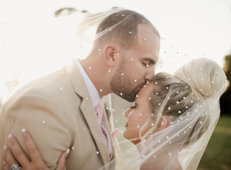 bride and groom kissing under her wedding veil