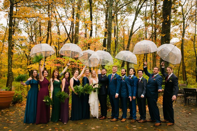 Wedding party posing with  clear umbrellas during a rain storm