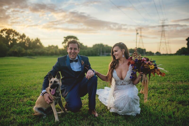bride and groom in a field with their dog