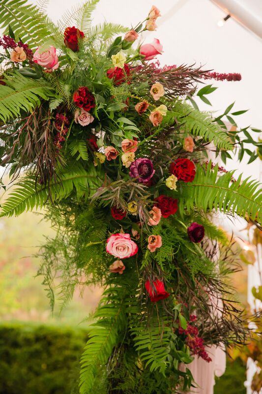 floral swags with ferns and pink and burgundy flowers on a wooden wedding arbor