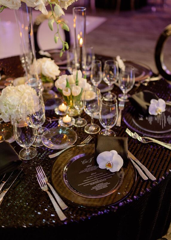 An elegant, modern black and white tablescape with white floral centerpieces and custom menu cards