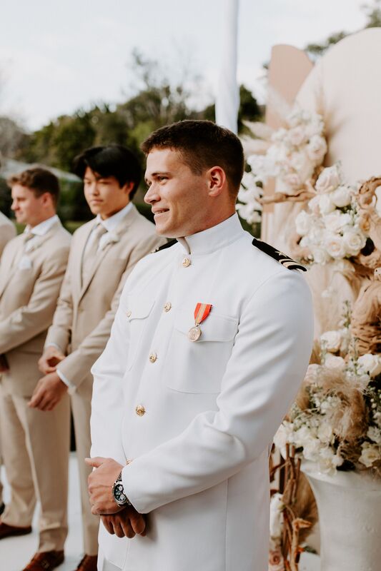 Military groom watching as his bride walks down the aisle