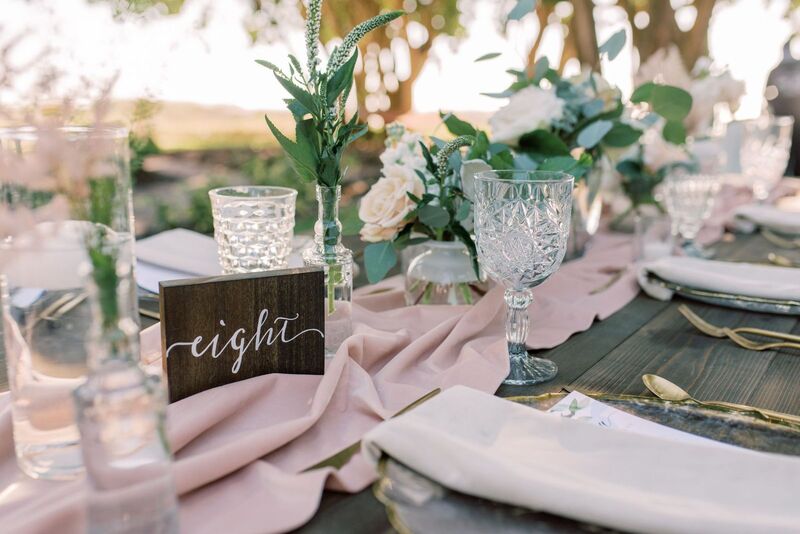 Rustic wooden table numbers paired with soft romantic pink florals and vintage glassware for an outdoor Siesta Key wedding