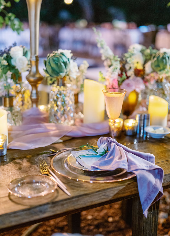 wedding tablescape set with gold rimmed china, luxurious napkins and tons of candles