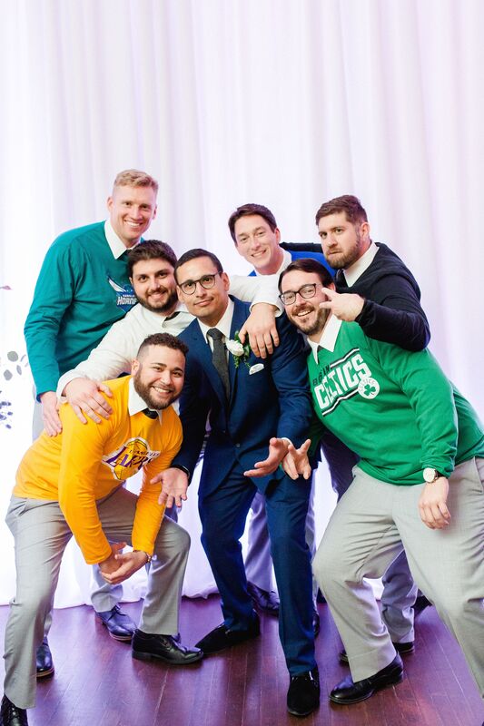 Groom posing for photos with his groomsmen wearing their favorite basketball teams shirts