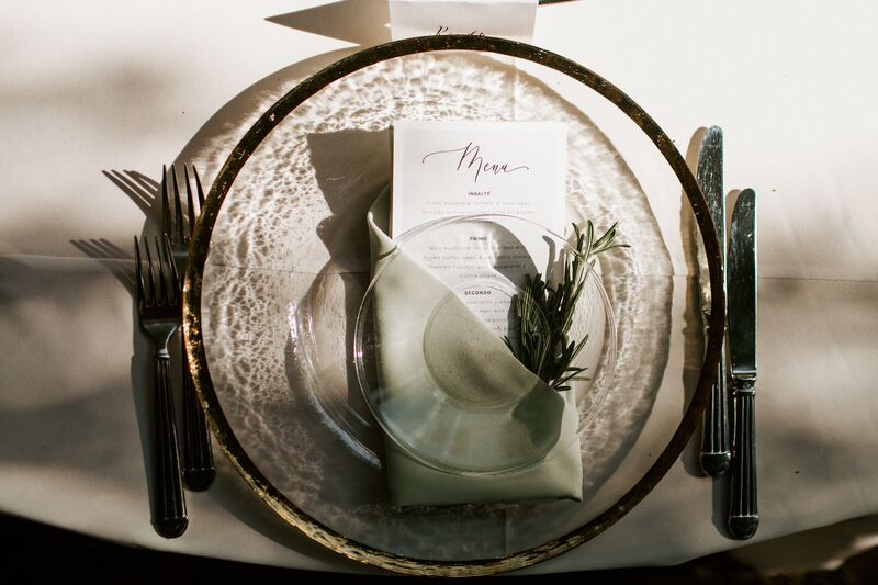 gold rimmed glass charger plate with sage napkin and fresh herbs at a Selby Gardens outdoor wedding reception