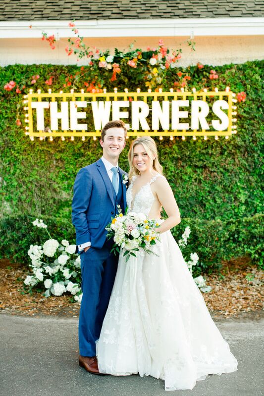 bride and groom standing under a custom designed neon sign 