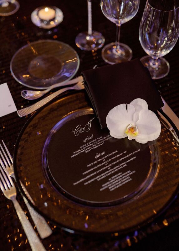 An elegant, modern black and white tablescape with white floral centerpieces and custom menu cards