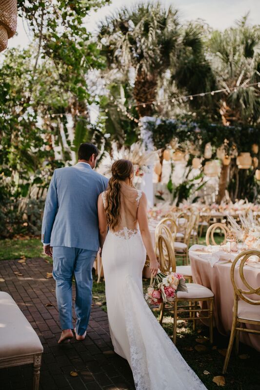 bride and groom taking a sneak peek at their Siesta Key beach-Boho outdoor reception in blush, coral and taupe with gold accents