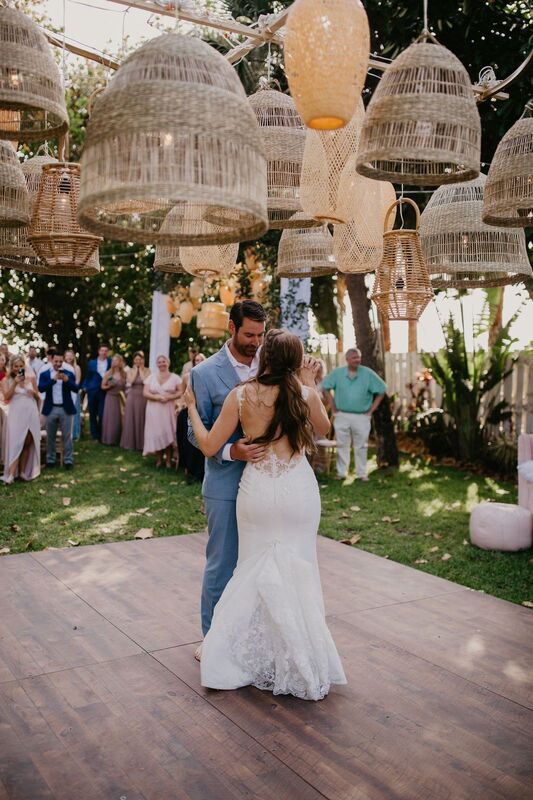 bride and groom during their first dance under a dozen rattan basket lights