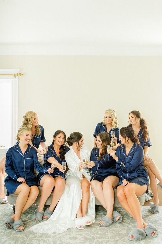 bride and bridal party wearing robes as they cheers with champagne