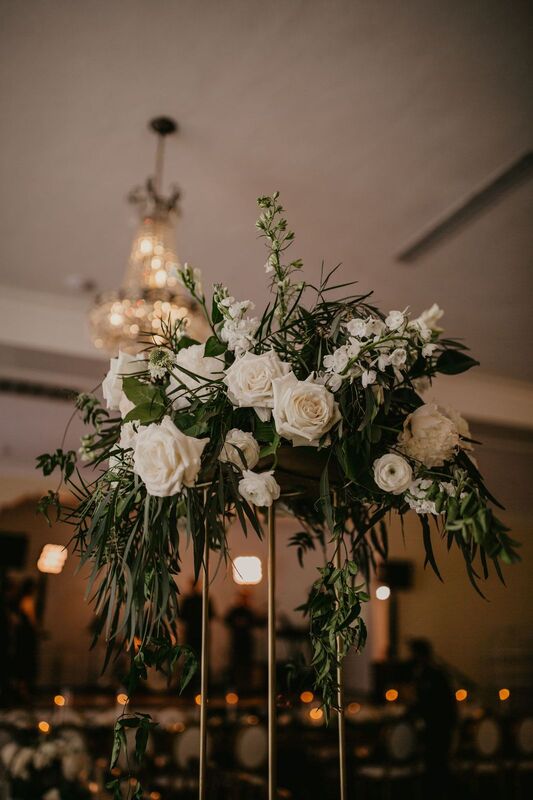 Tall gold risers with greenery and white flowers