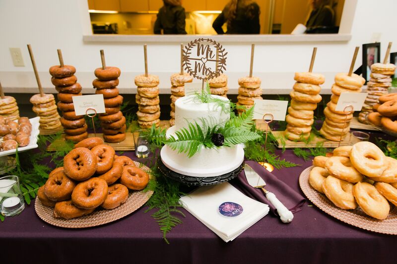 Vegan wedding cake surrounded by vegan and regular donuts
