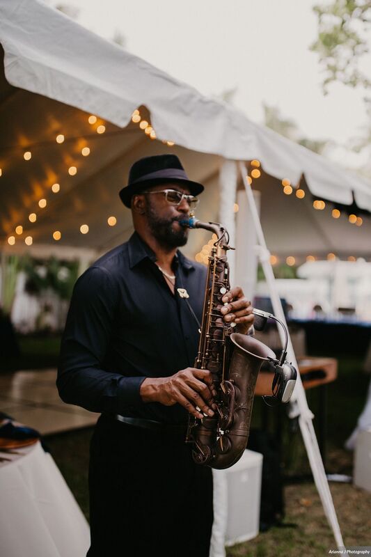 Musician playing sax for cocktail hour at a Sunset Beach Resort wedding