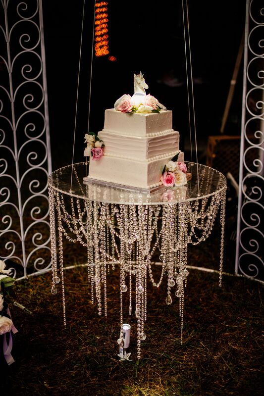 three tiered square white wedding cake floating on a glass table with crystals