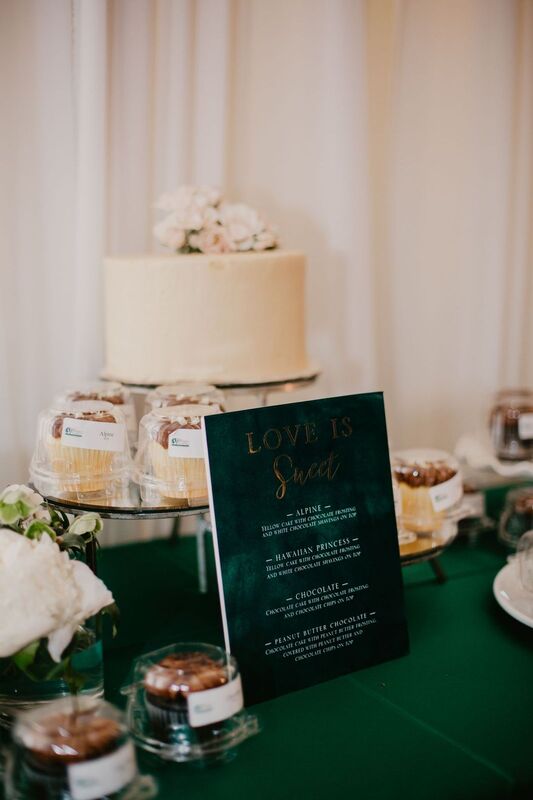 Intimate wedding cake surrounded by a display of cupcakes