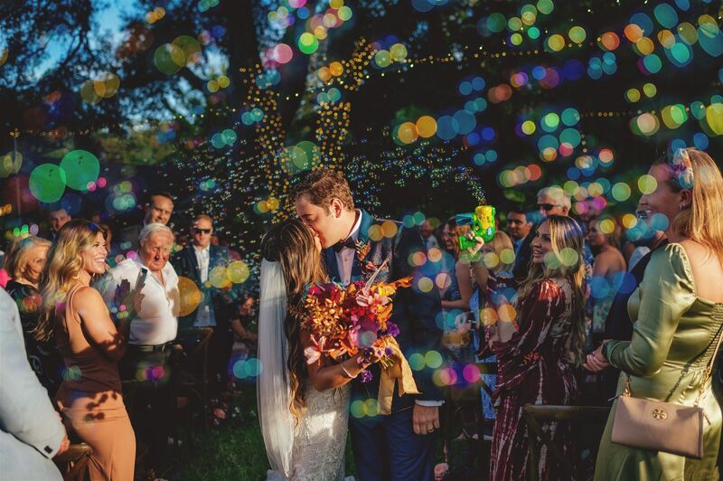 bride and groom surrounded by bubbles as they seal their vows with a kiss