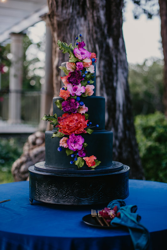 Matte black wedding cake with jewel tone sugar flowers by Cakes By Ron at Marie Selby Gardens