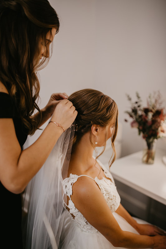hair stylist putting a veil in a bride's hair