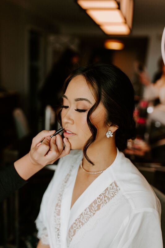 bride having makeup touched up on her wedding day