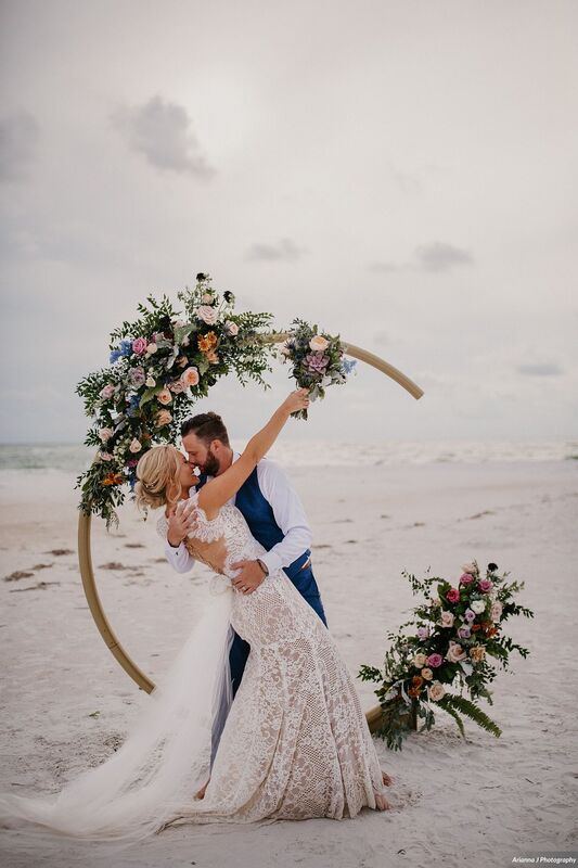 Groom kissing his bride at the end of their Sunset Beach Resort beach wedding