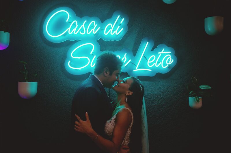 bride and groom kissing in front of a custom neon sign