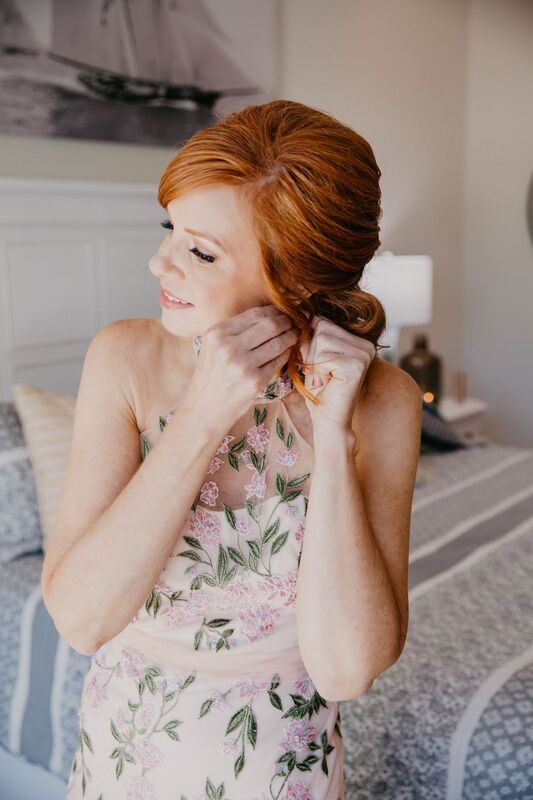 Sarasota bride wearing an elegant embroidered gown putting on her earrings