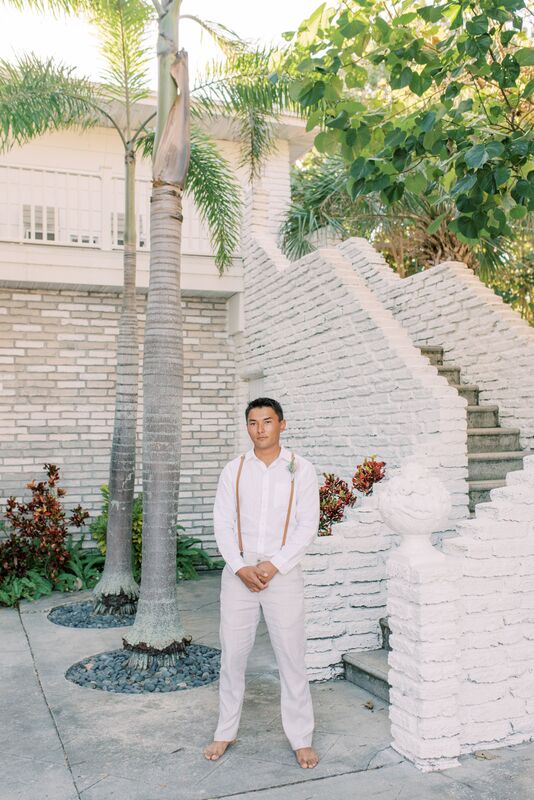 Groom wearing linen slacks, white shite and suspenders waiting for his bride's arrival for their first look