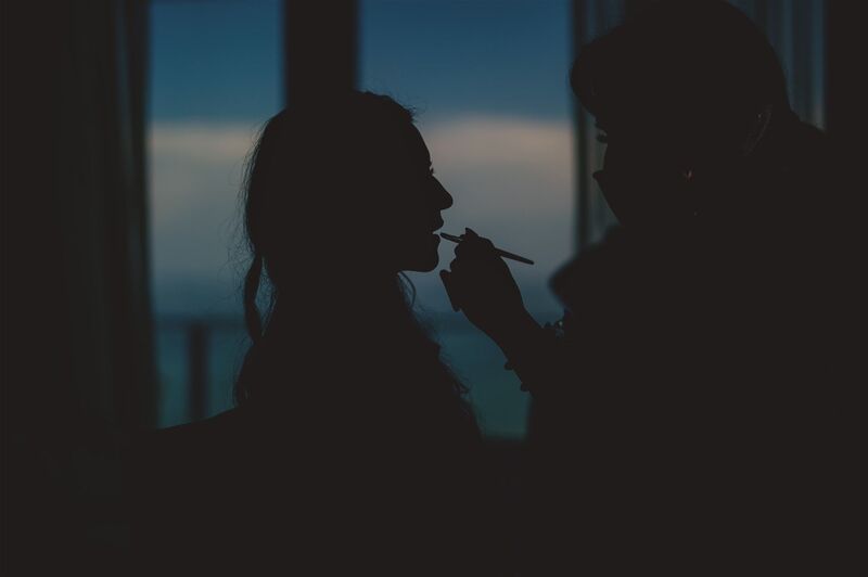 silhouette of bride getting lipstick applied 