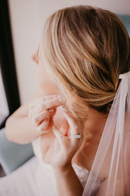 bride putting on diamond earrings