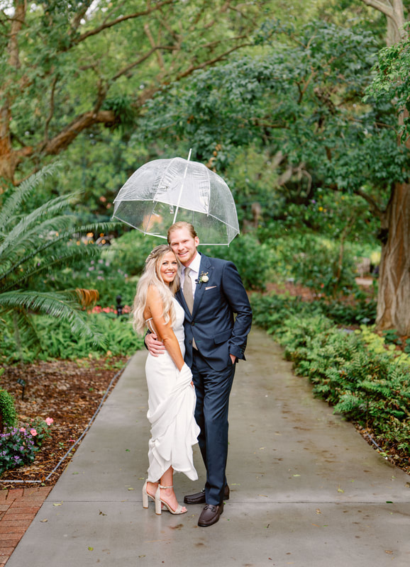 bride and groom walking under a clear umbrella at Selby Gardens