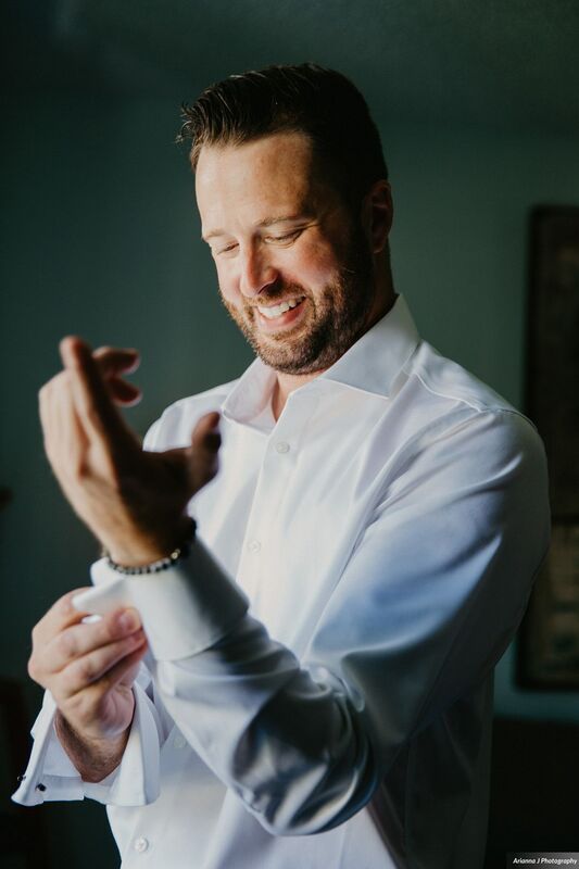 groom buttoning shirt on his wedding day