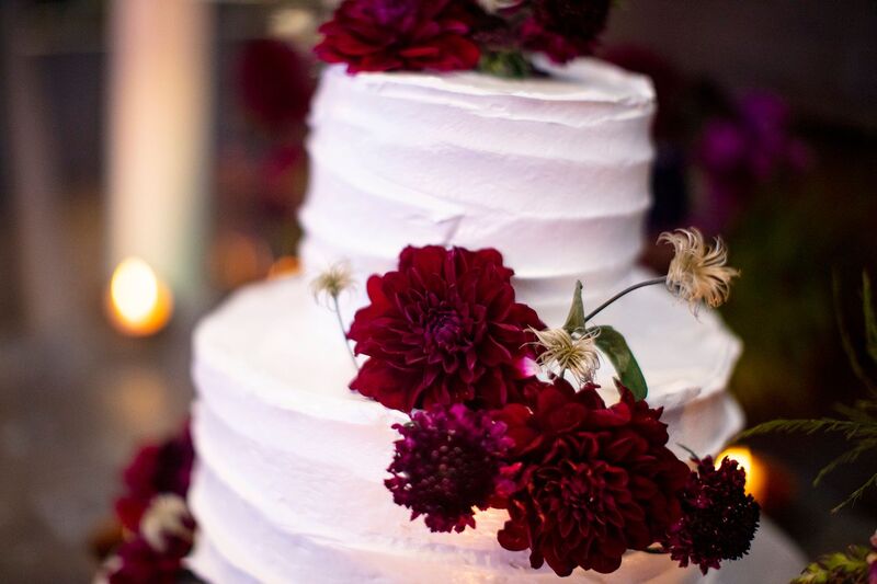 white buttercream wedding cake with burgundy flowers