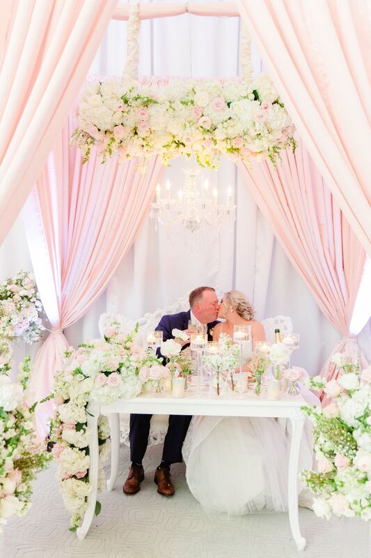Jennifer Matteo Event Planning – Lakewood Ranch – Lakewood Ranch wedding – The Lake Club – A wedding at The Lake Club – Pink and white wedding – Florida luxury weddings- Sarasota wedding planner- bride and groom kissing - bride and groom at sweetheart table - 